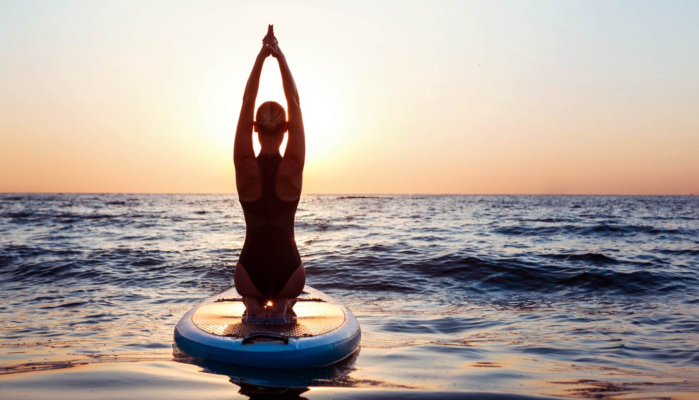 Top 5: Yoga and surf holidays around the world - Woman in a yoga pose on a surf board