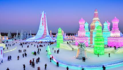 People admiring colourful lights in the ice buildings