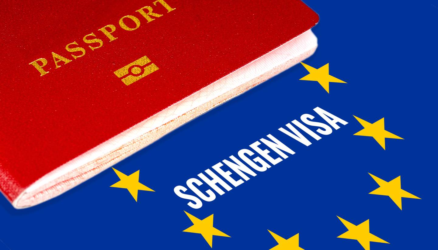 A guide to Schengen visas - Red passport on Europe flag background with Schengen Visa in the circle of stars