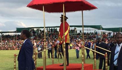 King Mswati III on a red and gold podium surrounded by bodyguards