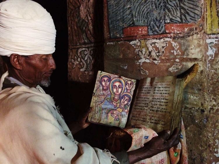 The priest holding the holy book Teamre Mariam (Miracle of St Mary)