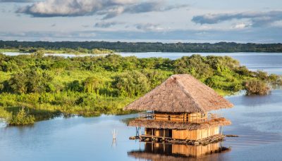 Aerial view of wooden hut on a river in the Amazon rainforest