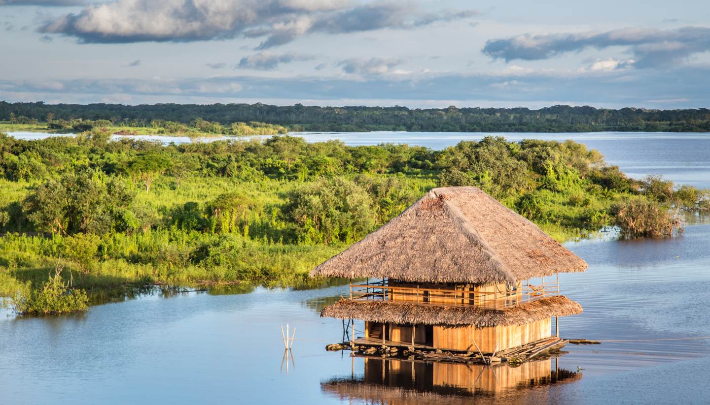 Peru: Secrets of the Amazon - Aerial view of wooden hut on a river in the Amazon rainforest