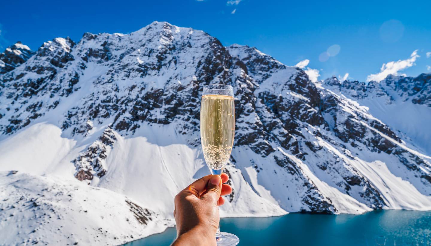 Top 10 luxury ski resorts around the world - Person holding champagne - background mountain